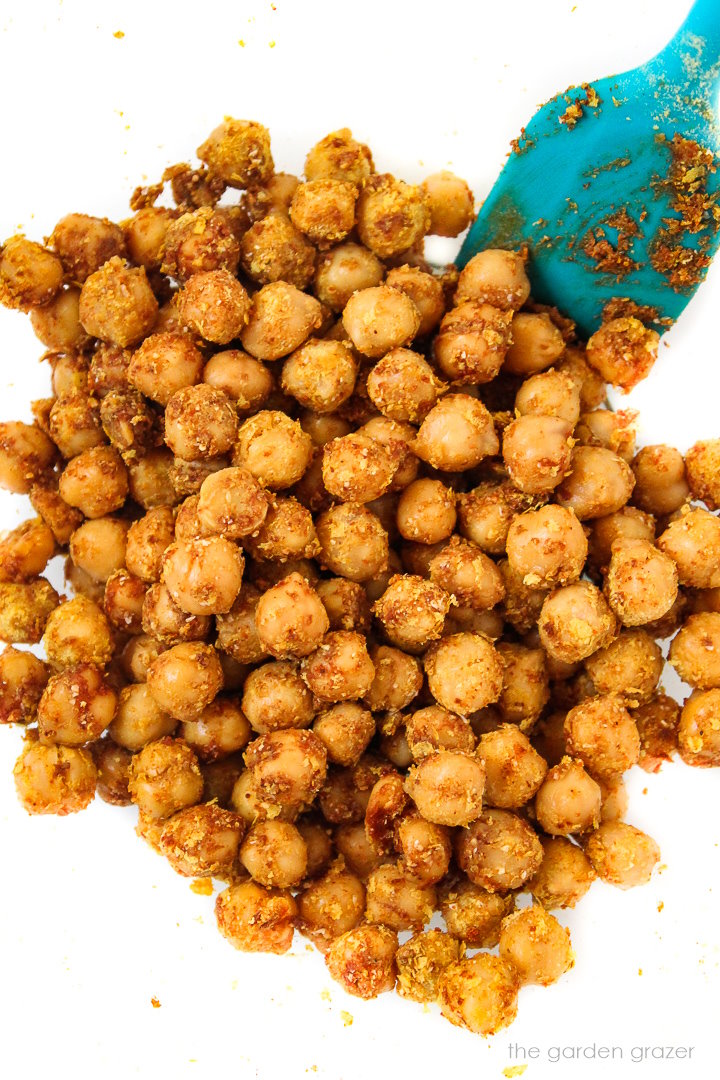 Cheesy nacho chickpeas stirred together with a blue spatula before roasting