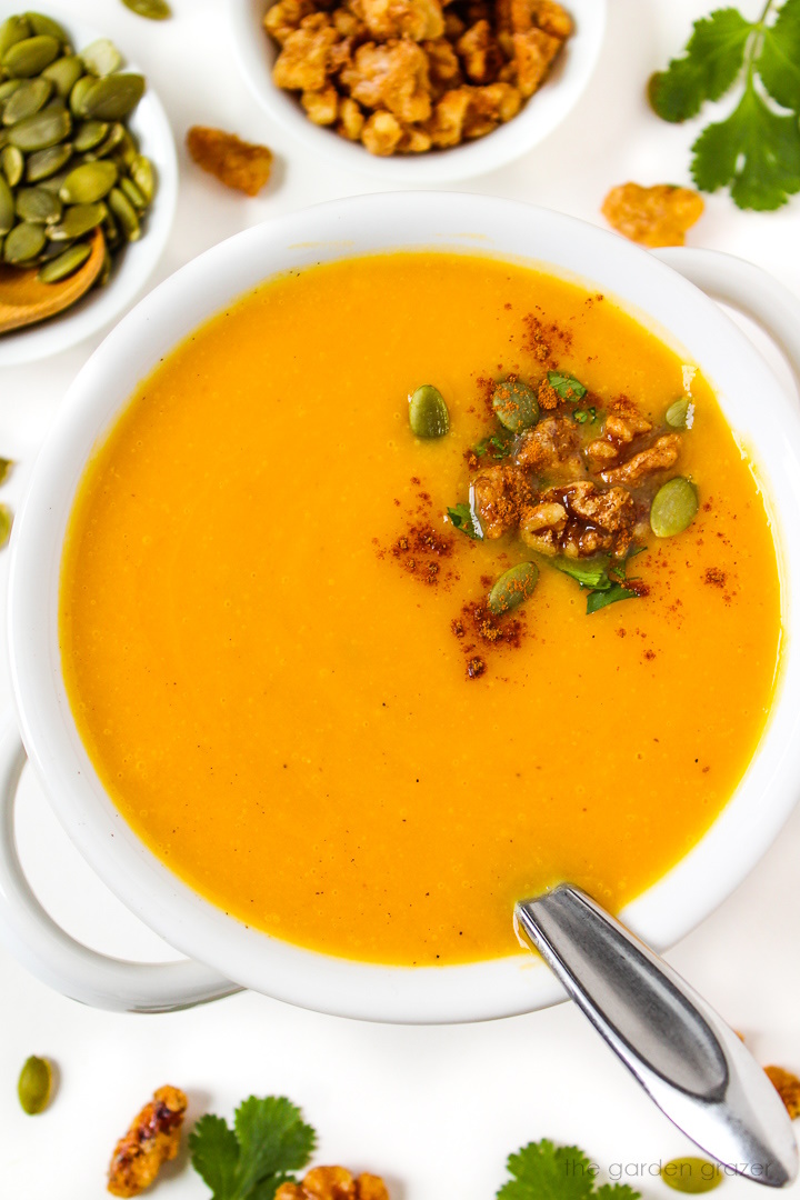 Vegan butternut squash soup in a white serving bowl topped with candied walnuts