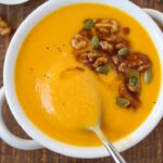 Roasted butternut squash soup in a white serving bowl on a wooden table