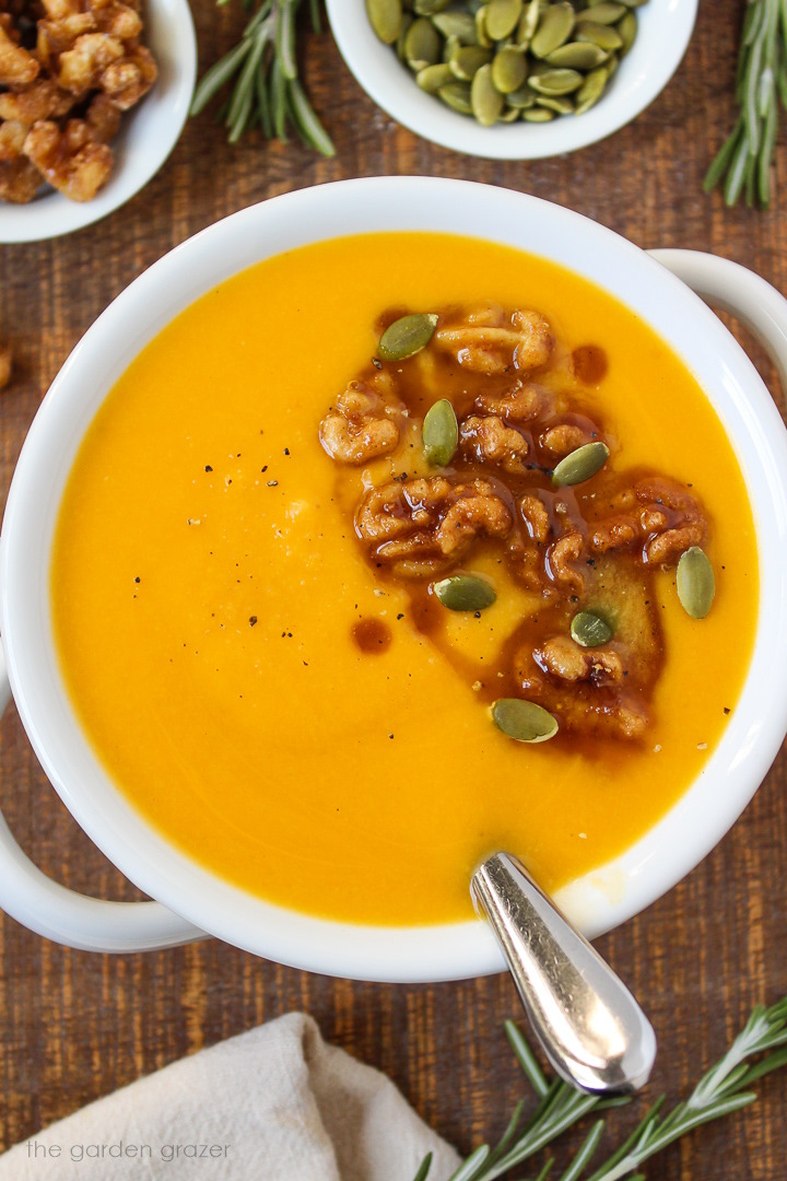 Overhead view of vegan roasted butternut squash soup in a white bowl with serving spoon