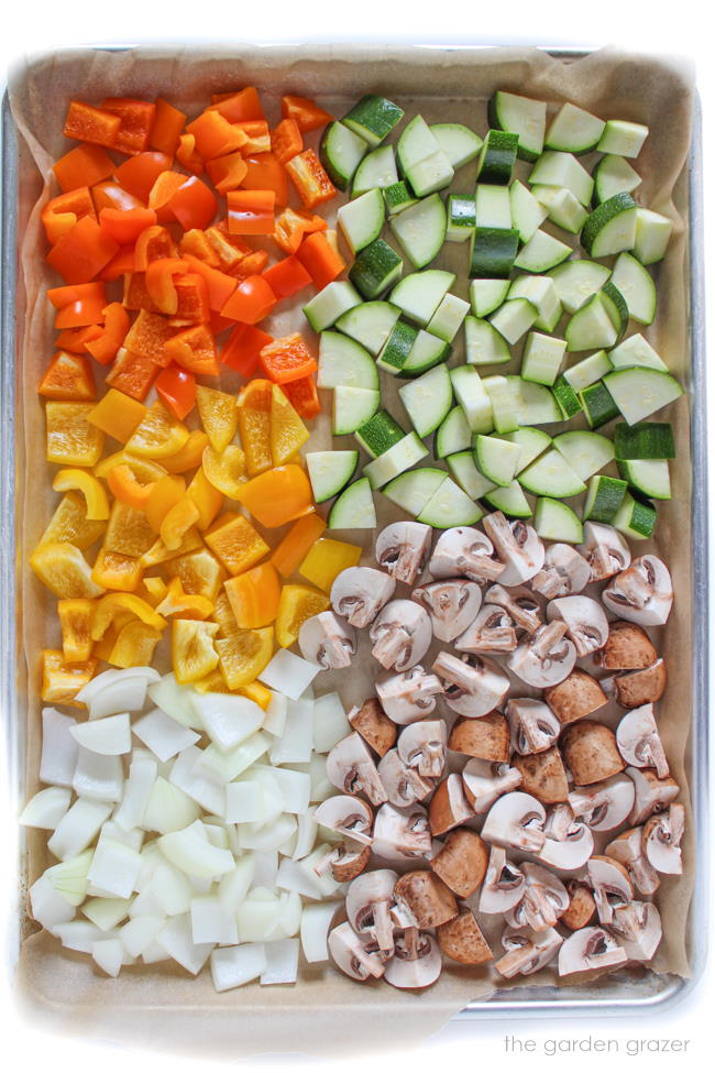 Assortment of raw, diced vegetables on a baking pan