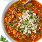 Bowl of stuffed pepper lentil soup topped with brown rice and fresh parsley