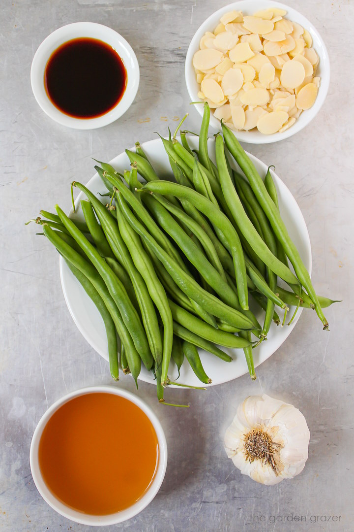 Fresh beans, garlic, sliced almonds, broth, and tamari ingredients laid out on a metal tray