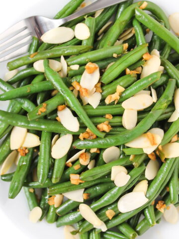 Almond green beans on a white plate with fork