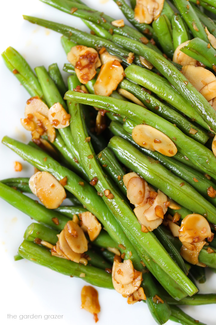 A close-up overhead view of cooked green beans on a white plate
