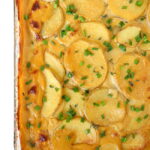Pan of baked vegan scalloped potatoes garnished with chives