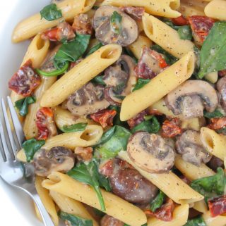 Creamy sun-dried tomato mushroom pasta in a bowl with fork