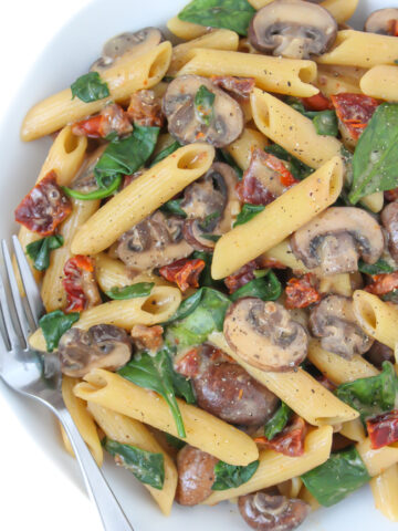 Creamy sun-dried tomato mushroom pasta in a bowl with fork