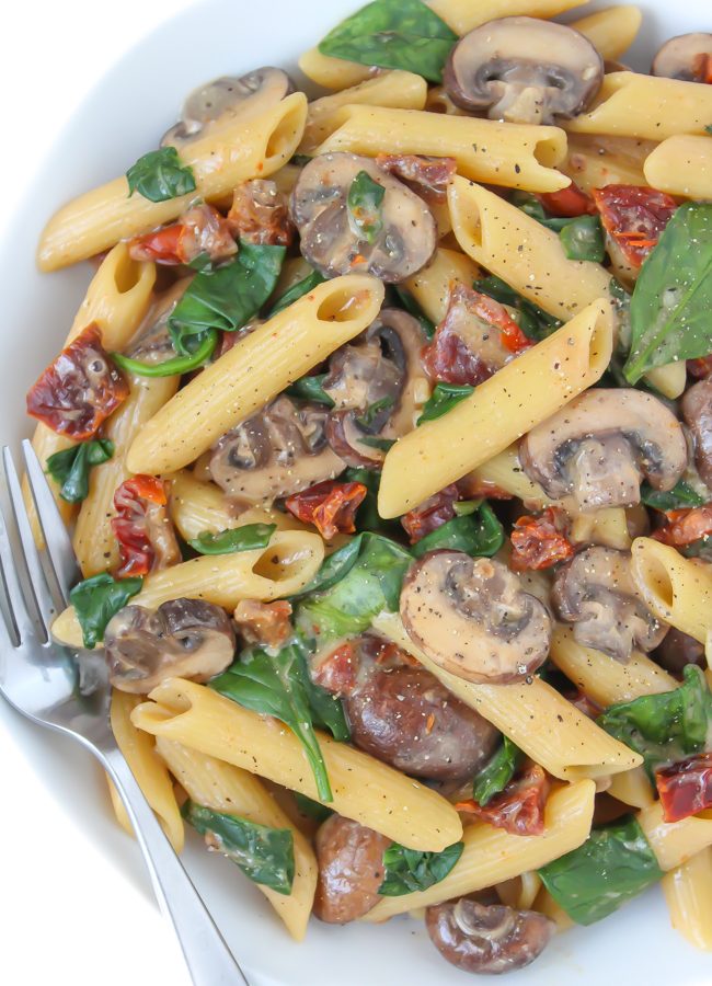 Creamy sun-dried tomato mushroom pasta in a bowl with fork