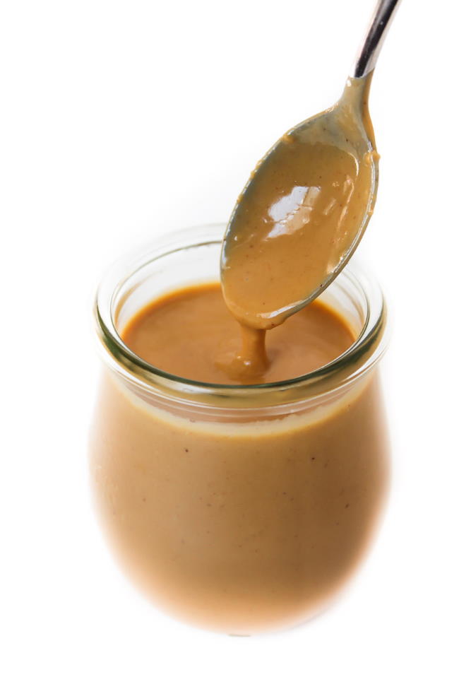 Small glass jar filled with creamy Thai Peanut Sauce and a spoon