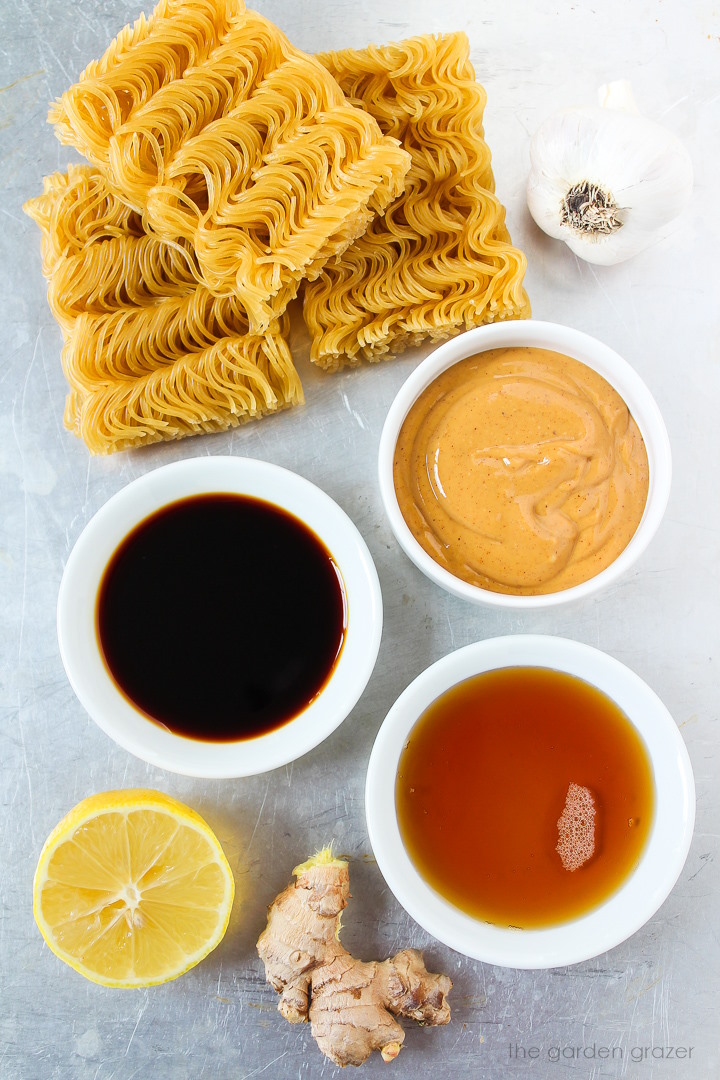 Ramen noodles, peanut butter, tamari, ginger, garlic, and fresh lemon ingredients laid out on a metal tray