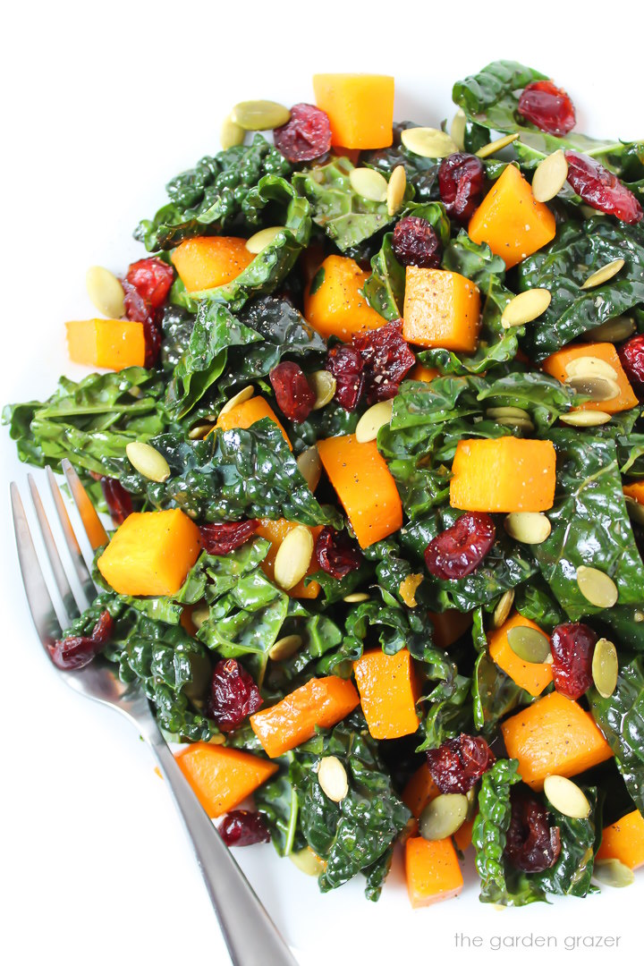 Overhead view of butternut squash kale salad on a white plate with serving fork