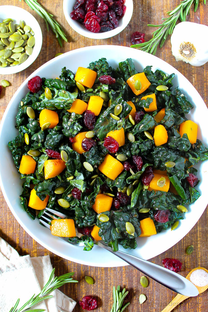 Kale and butternut squash salad tossed in a rosemary balsamic dressing served on a white plate