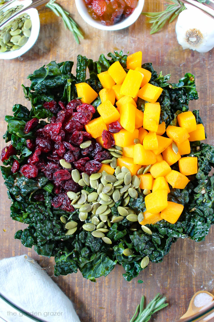 Overhead view of preparing salad ingredients together in a glass bowl before mixing together
