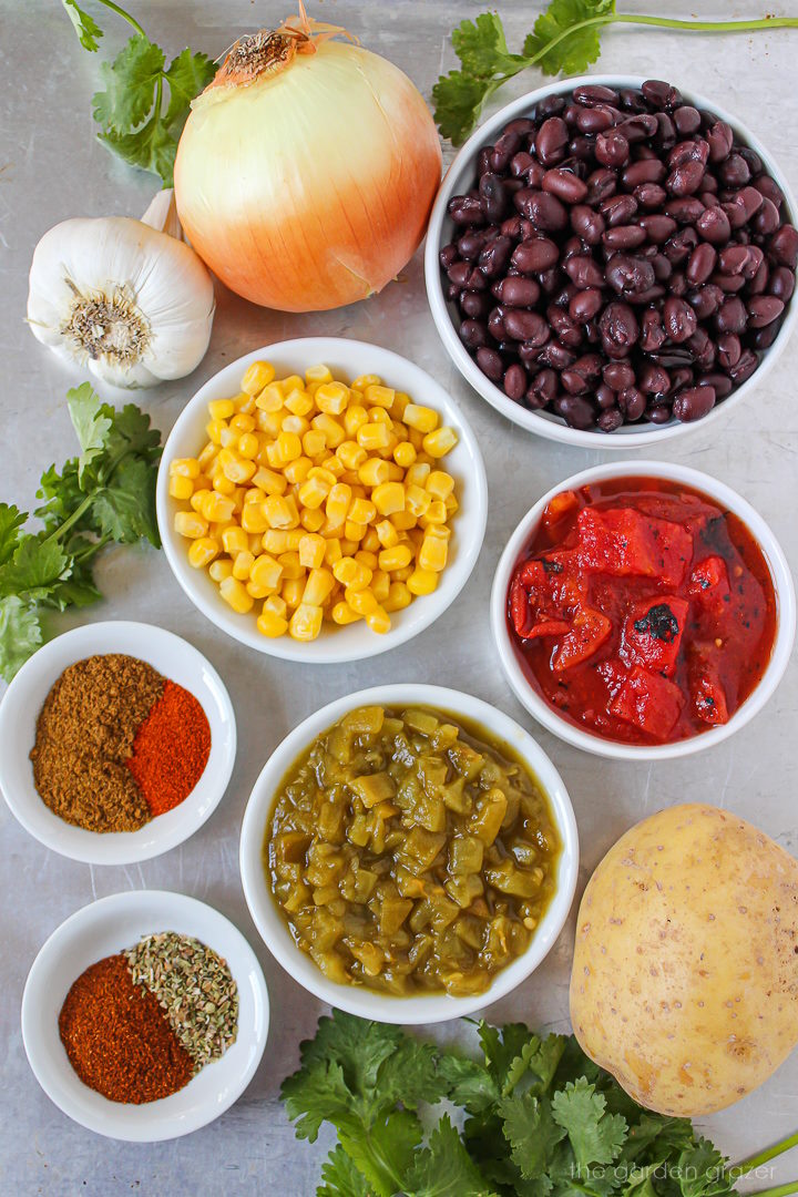 Beans, sweet corn, tomatoes, potato, onion, and spice ingredients laid out on a metal tray