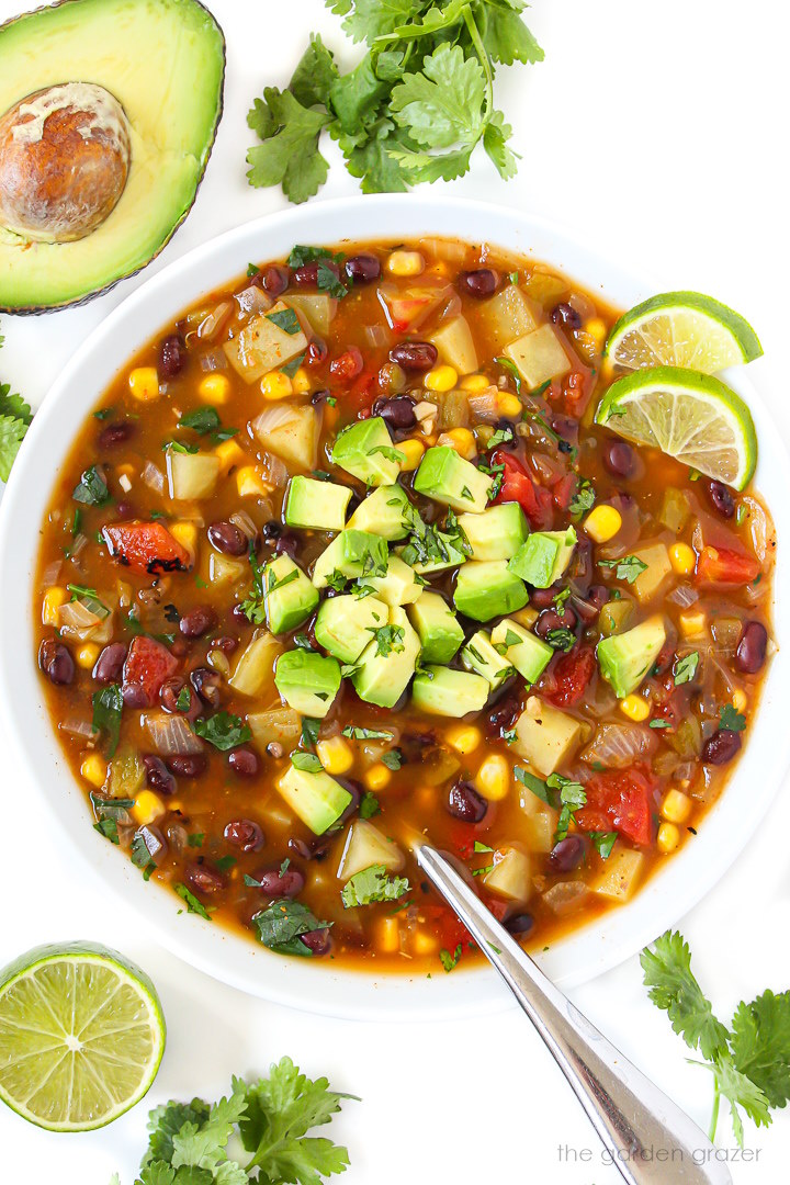 Southwest black bean soup in a white bowl garnished with avocado, cilantro, and lime slices