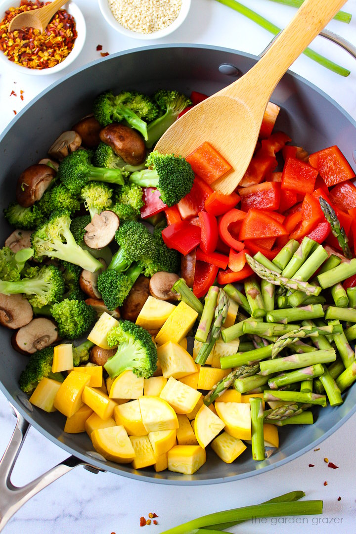 Overhead view of preparing vegetable stir fry in a large skillet before mixing together