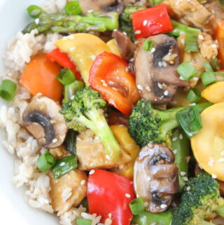 Vegetable tempeh teriyaki stir fry in a bowl with brown rice