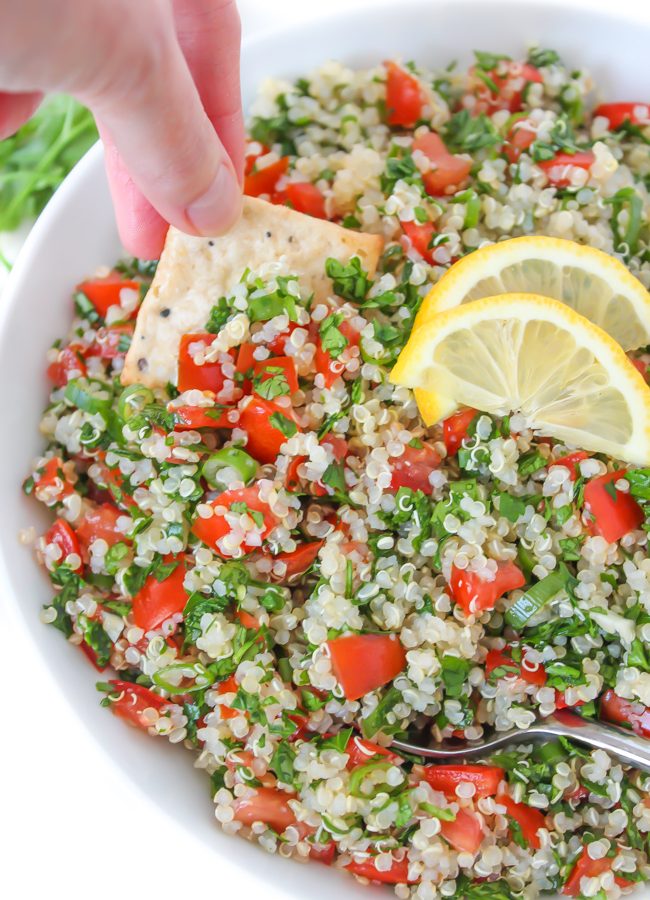 Cracker dipping into bowl of quinoa tabbouleh salad