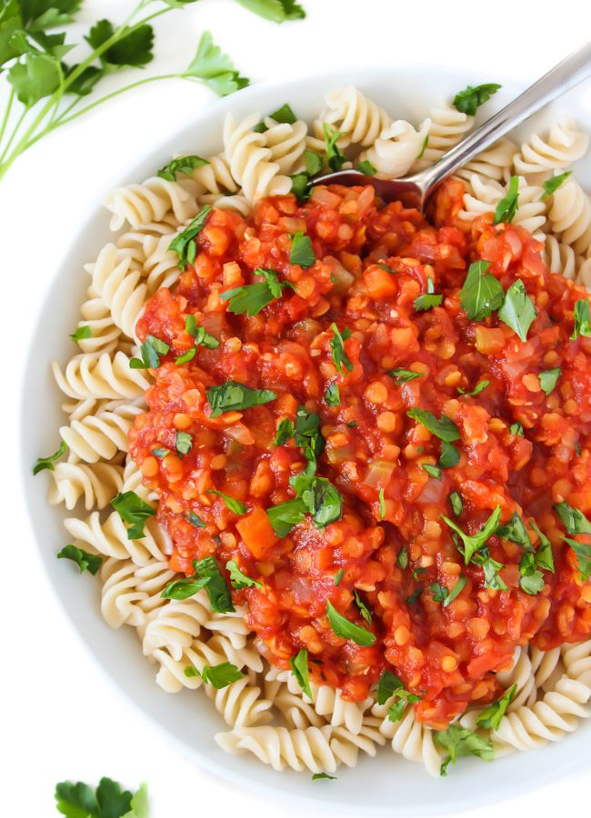Bowl of vegan lentil bolognese sauce over pasta topped with parsley