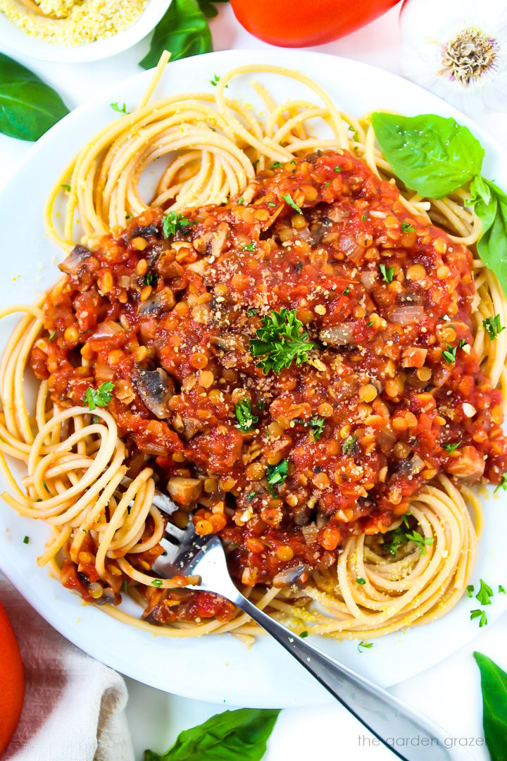 Vegan lentil and mushroom Bolognese sauce on top of spaghetti noodles on a white plate