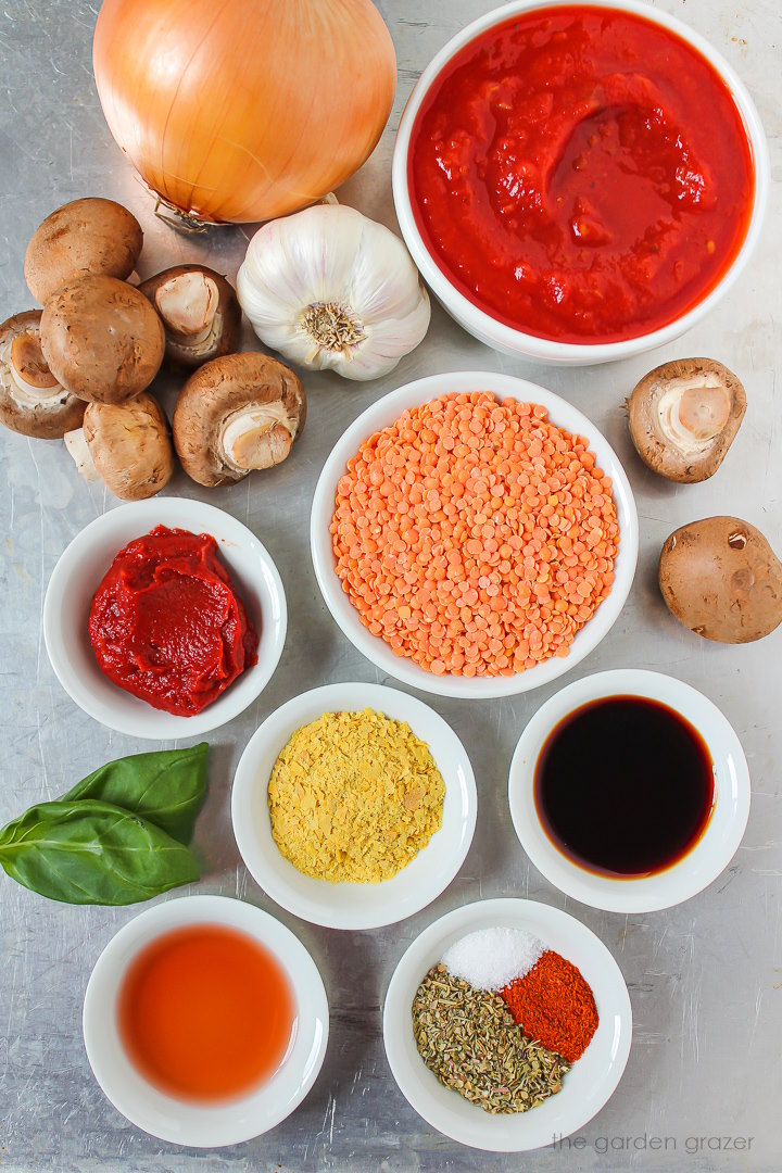 Red lentils, crushed tomatoes, mushrooms, onion, garlic, tomato paste, and spice ingredients laid out on a metal tray