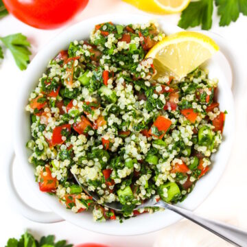 Overhead view of quinoa tabbouleh salad in a white bowl with lemon slice
