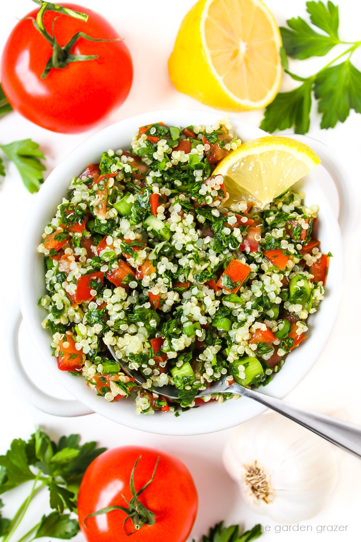 Overhead view of quinoa tabbouleh salad in a white bowl with lemon slice