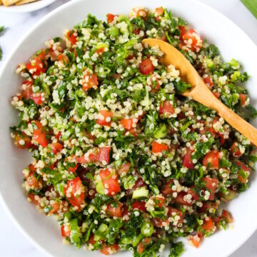 Overhead view of quinoa tabbouleh served in a white bowl with side of crackers