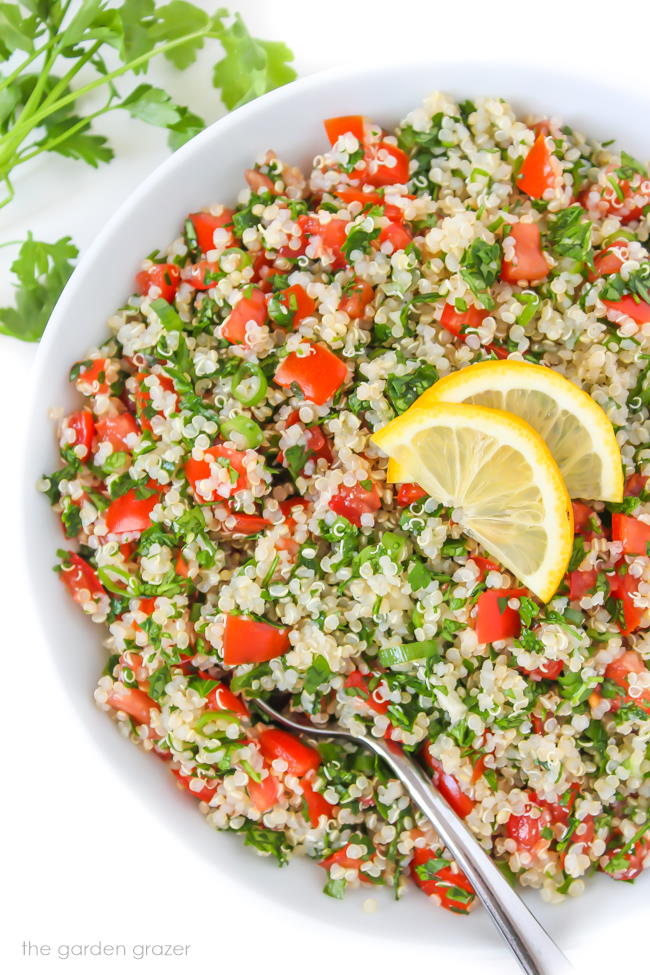 Oil-free vegan quinoa tabbouleh in a bowl with lemon slices