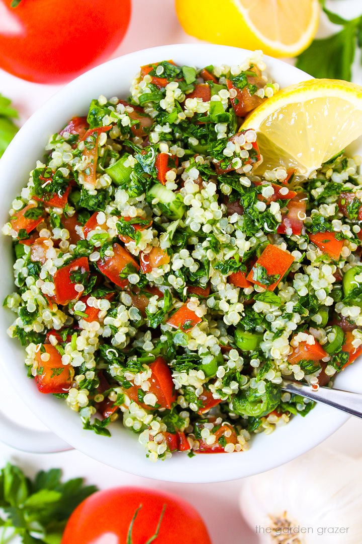 Close-up view of quinoa tabbouleh with tomato and parsley in a white bowl