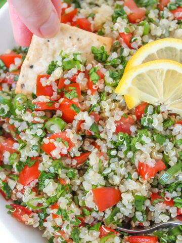 Quinoa tabbouleh with tomato and parsley in a white bowl