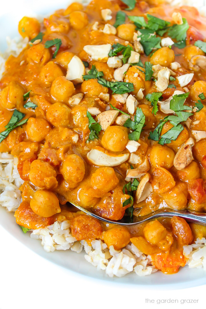 Close up view of vegan butter chickpeas in a white bowl with serving spoon