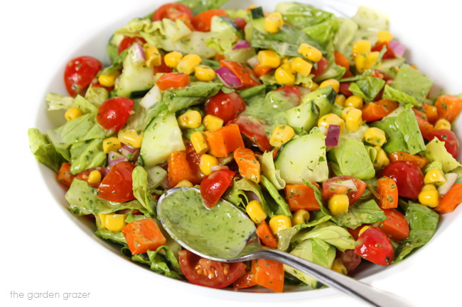 Fresh salad in a white bowl tossed with creamy herb dressing