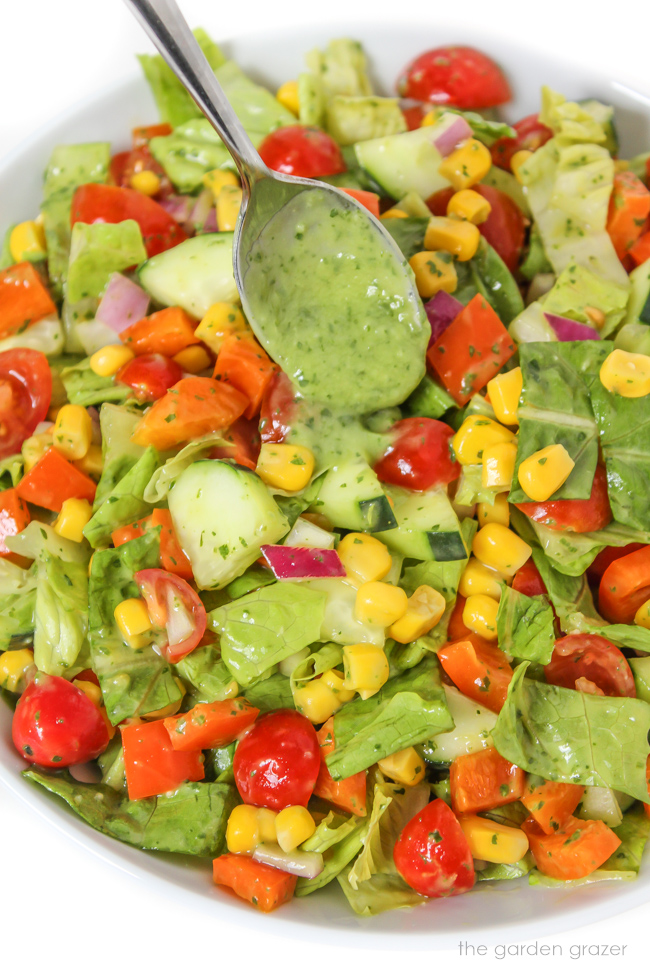 Vegan summer chopped salad tossed with herb dressing on a plate with spoon