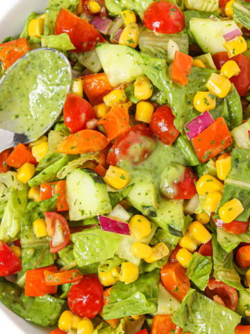 Summer salad with herb dressing in a white bowl with spoon