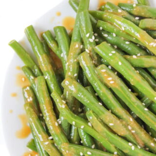 Vegan miso-glazed green beans on a plate with sesame seeds