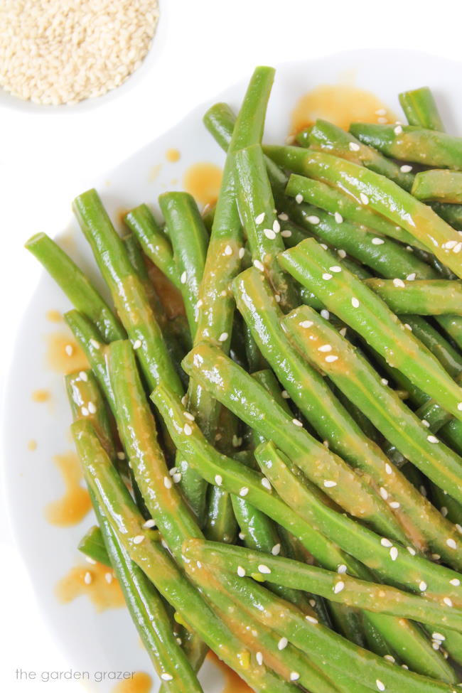 Vegan miso-glazed green beans on a plate with sesame seeds