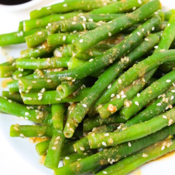 Close up view of miso glazed green beans on a white plate