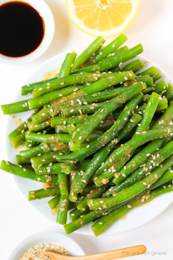 Overhead view of miso green beans on a white plate with sesame seeds