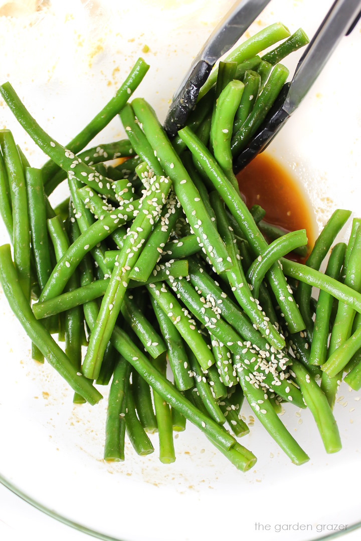 Preparing miso green beans in a large bowl with sesame seeds