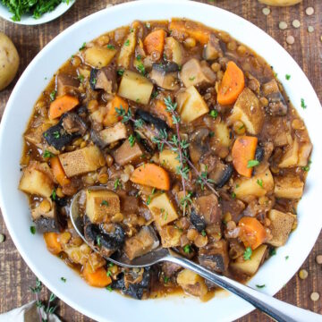 A white bowl of Portobello Mushroom Stew with chunky lentils, potatoes, and carrots