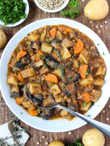 A white bowl of Portobello Mushroom Stew with chunky lentils, potatoes, and carrots
