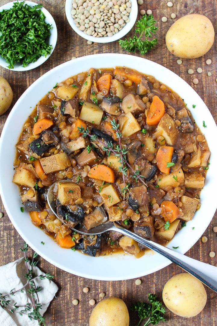 A white bowl of vegan beef stew made with Portobello Mushroom, chunky lentils, potatoes, and carrots