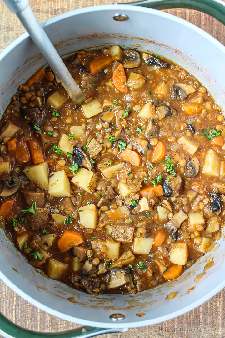 Overhead view of Portobello mushroom vegan "beef" stew with lentils and potatoes cooking in a large pot