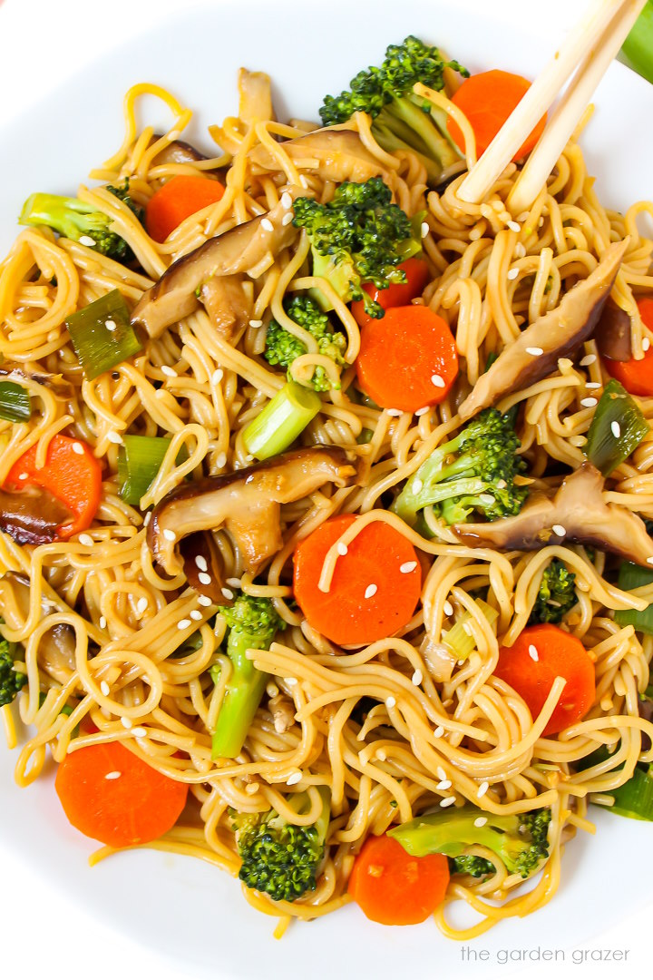 Close-up view of vegan Teriyaki noodles on a white plate with chopsticks