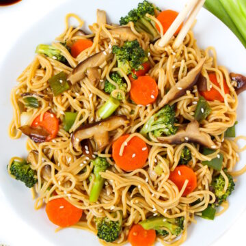 Teriyaki noodles with vegetables on a white plate with chopsticks