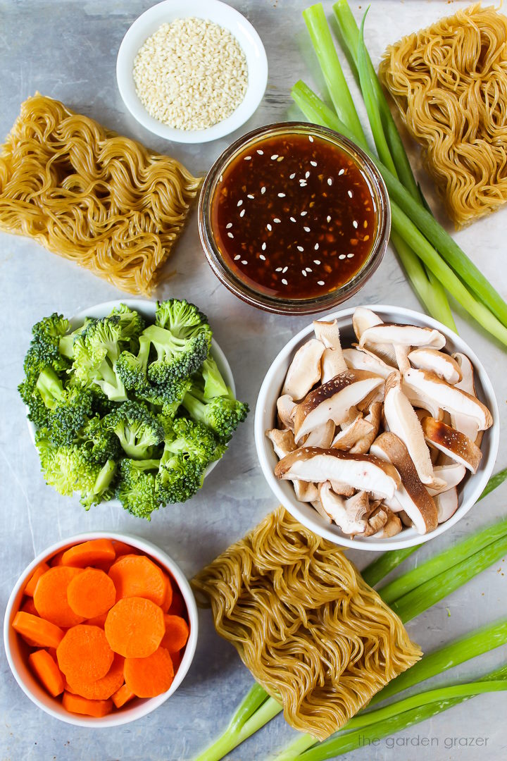 Ramen, sauce, mushrooms, broccoli, and carrot ingredients laid out on a metal tray