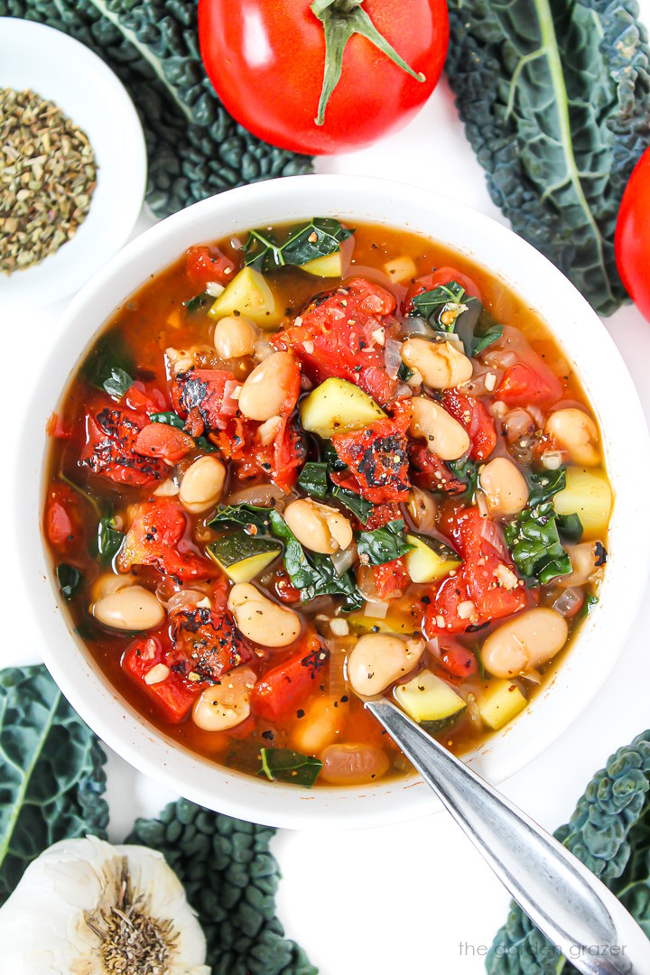 White bean tomato soup with kale in a white bowl with spoon