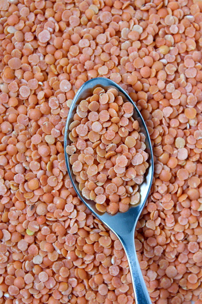 Close-up view of dry red lentils ingredient with a metal spoon